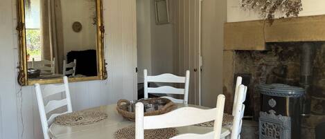 A dining area with a round table, white chairs, a large mirror, and a decorative wall piece.