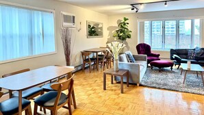 Una sala de estar moderna con comedor, ventanas amplias y vista a la ciudad.