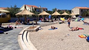 Een strand met parasols, zonnebathers en gebouwen op de achtergrond.