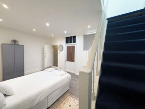 Quarto com cama, guarda-roupa, chuveiro e escada.