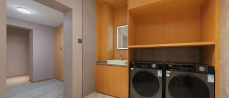 A compact laundry room with two washing machines, a sink, and wooden cabinetry.