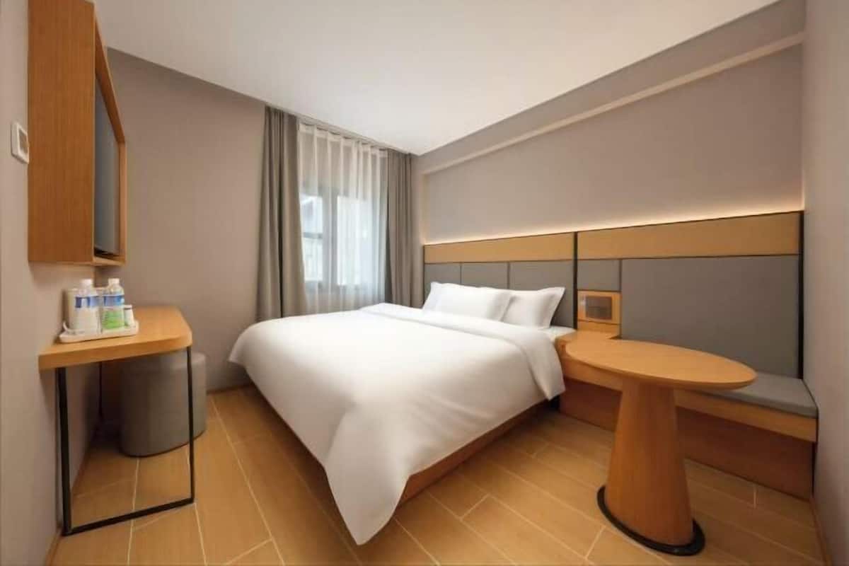Quarto de hotel com cama, mesa de cabeceira e uma pequena mesa redonda.