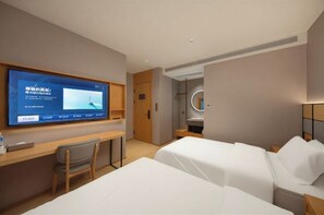 Een hotelkamer met een bed, een bureau met stoel, een televisie en een spiegel.