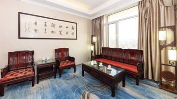 A traditional room with a sofa, two chairs, a coffee table, and a large framed calligraphy piece on the wall.