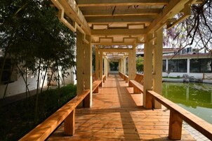 A wooden walkway with benches, leading to a pond.