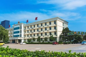 A multi-story building with a flat roof, several windows, and a parking lot in front. - Taixi Hotel (Feicheng)