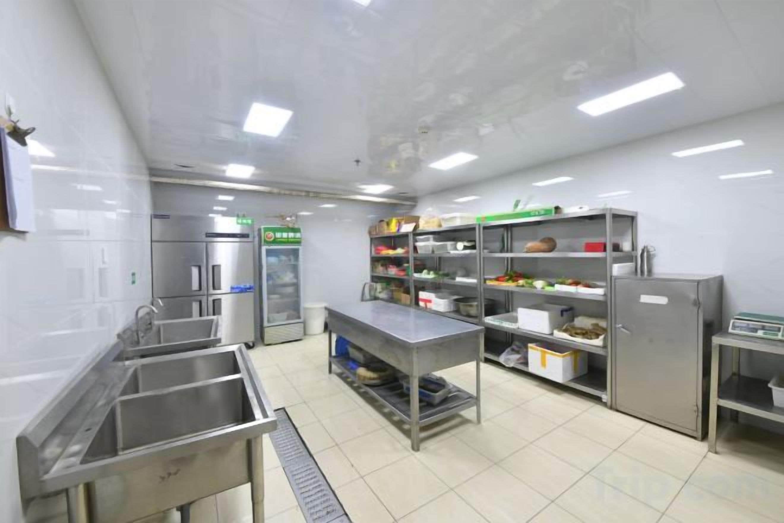 A commercial kitchen with stainless steel appliances, a sink, and storage shelves.