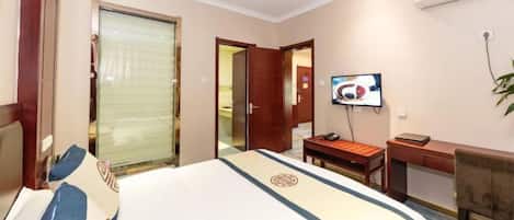 A hotel room with a large bed, a desk, a chair, a television, and a sliding door.