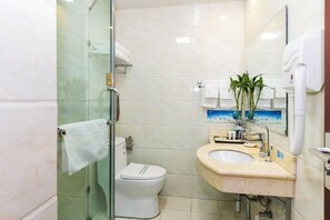 A bathroom with a glass shower enclosure, a toilet, a sink with a mirror, and a hand dryer. - Taixi Hotel (Feicheng)