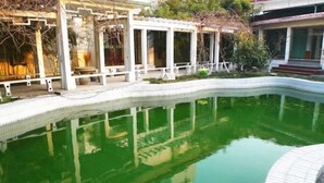 A swimming pool with a tiled edge, surrounded by a white pergola structure. - Taixi Hotel (Feicheng)