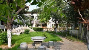 A garden with a stone bridge, a gazebo, and a round table with stools. - Taixi Hotel (Feicheng)
