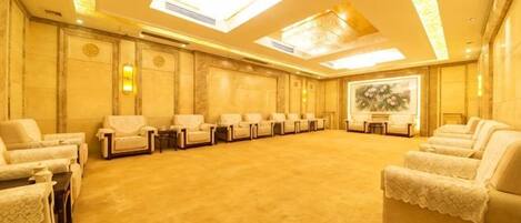 Un salón de conferencias con una larga mesa y sillas, piso alfombrado y un cuadro grande en la pared.