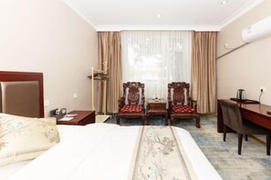 A hotel room with a bed, two wooden chairs, a desk, and a large window with curtains. - Taixi Hotel (Feicheng)