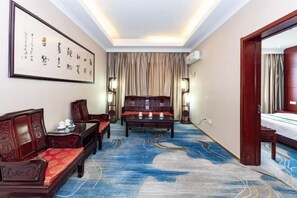 A traditional room with a sofa, a wooden table, and a bed. - Taixi Hotel (Feicheng)