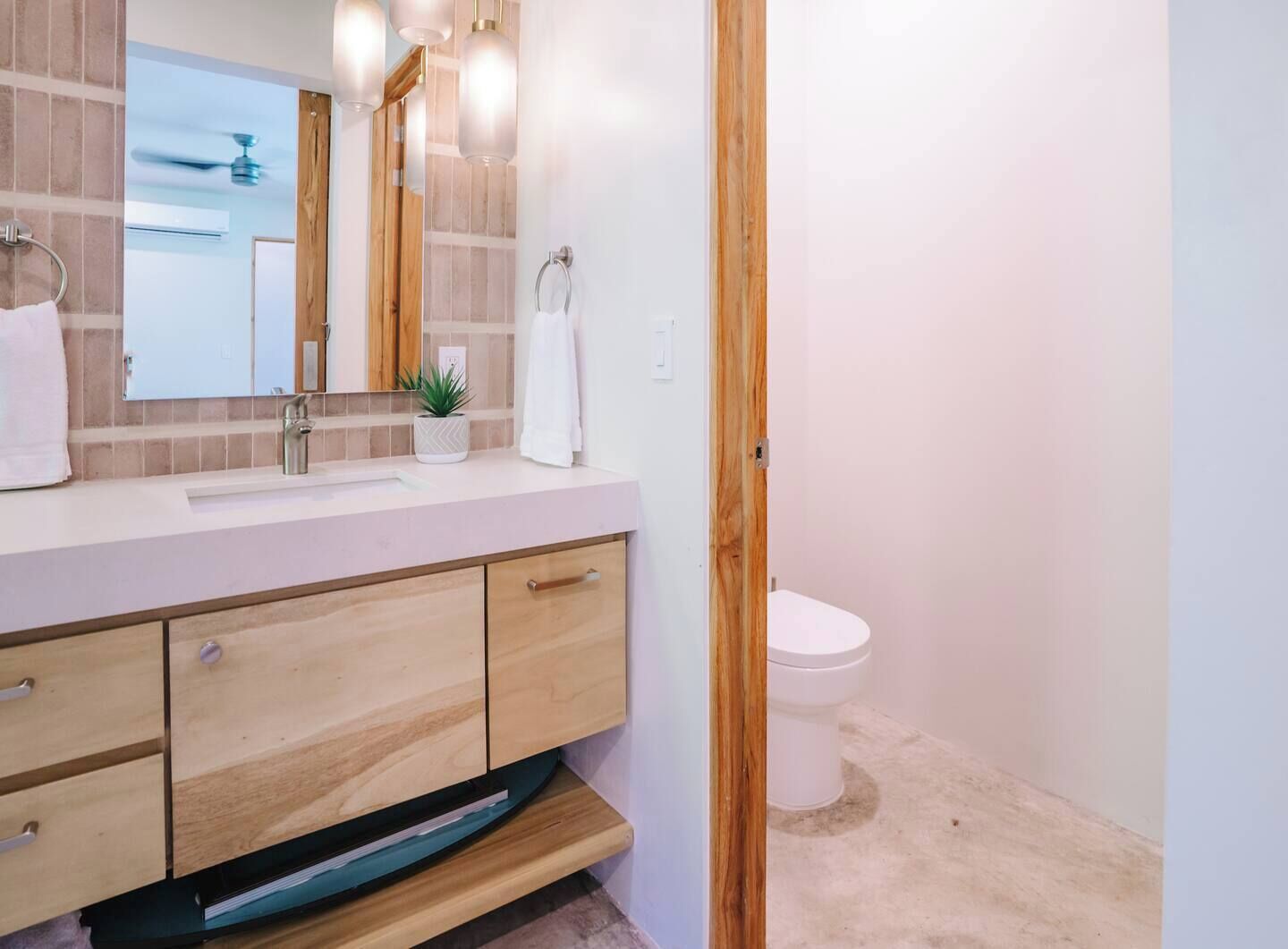 Un baño con tocador de madera, un lavamanos y un inodoro.