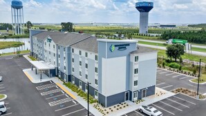 Ein modernes Hotel mit Parkplatz, einem Wasserturm und einem großen Gebäude im Hintergrund.