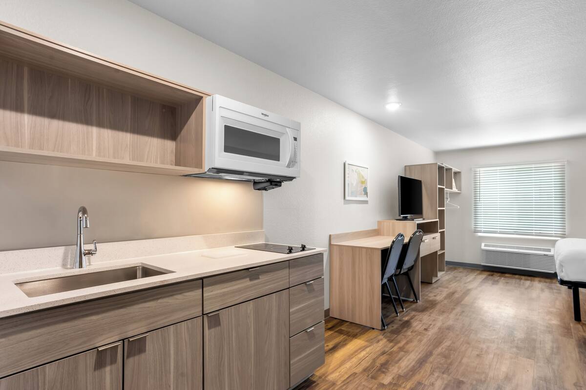 A modern kitchen with a microwave, sink, and wooden cabinets.