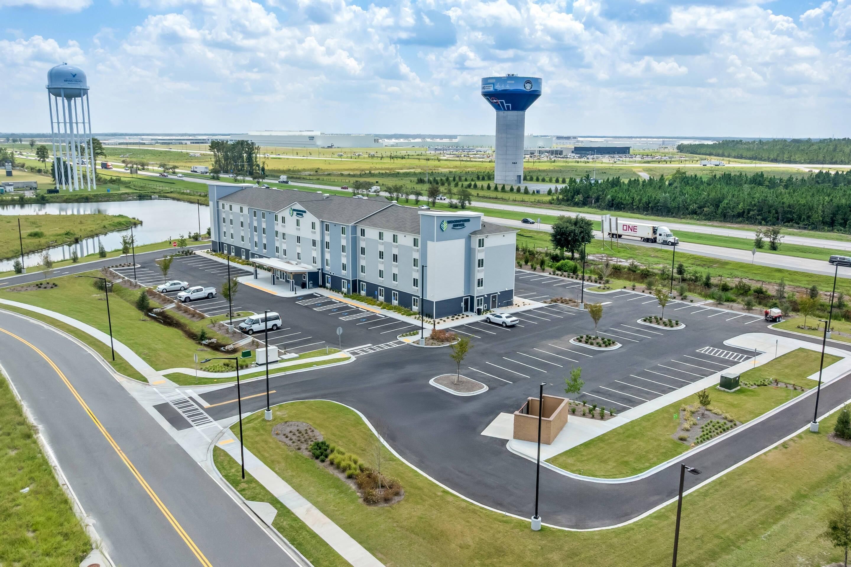 A hotel with a central parking lot, a water tower, and a large building with a blue roof.