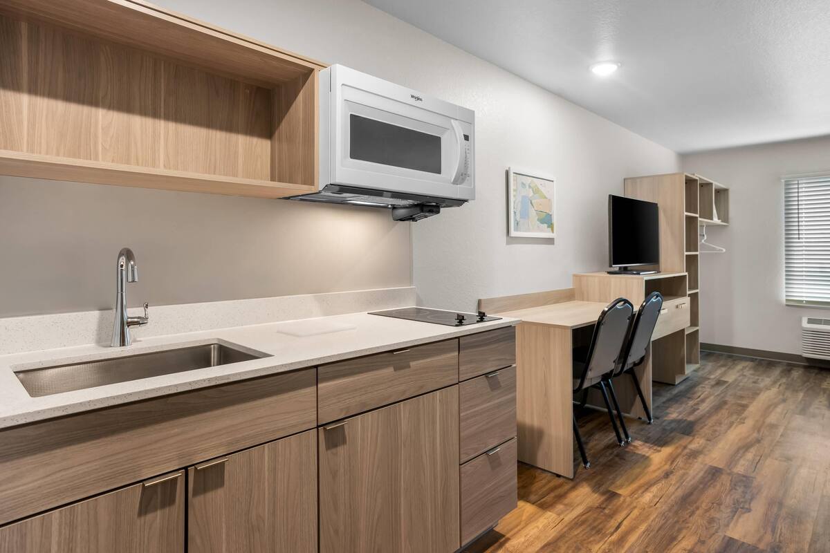 A modern kitchen with a microwave, sink, and wooden cabinets.
