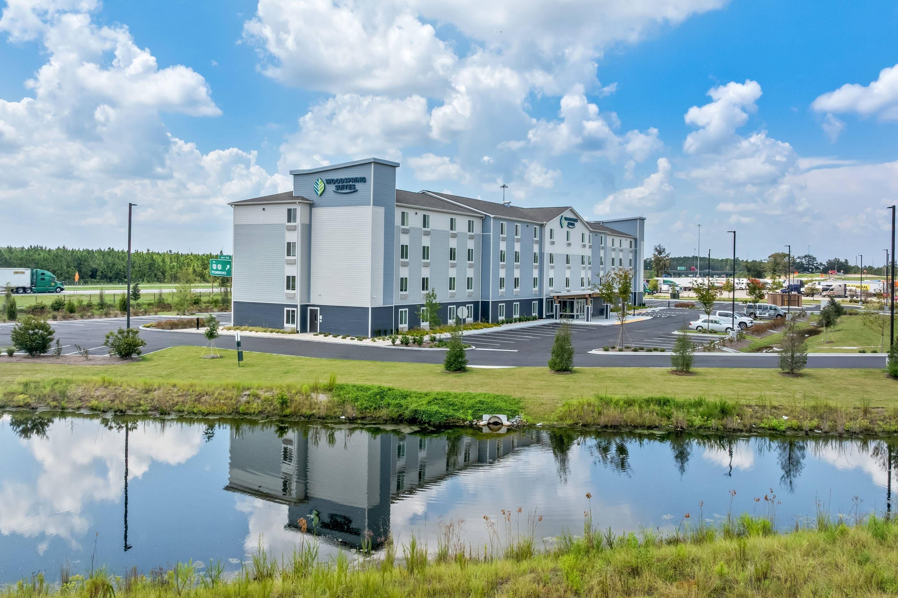 A modern hotel with a large building and a reflection in a pond.