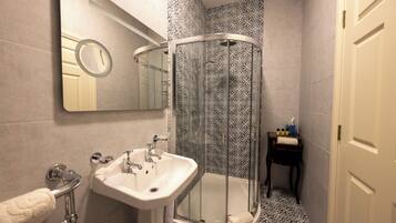 Un baño con ducha de vidrio, lavamanos y espejo.