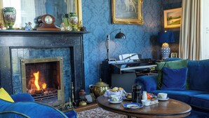 A cozy living room with a fireplace, blue furniture, and a coffee table with tea cups and pastries. - Noan Country House B and B (Noan)