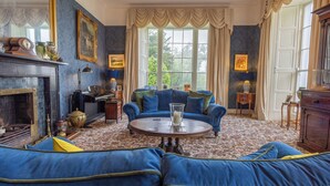 A room with a blue sofa set, a fireplace, and a large window with curtains. - Noan Country House B and B (Noan)