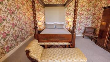A four-poster bed with a canopy, a bench, and two bedside lamps.
