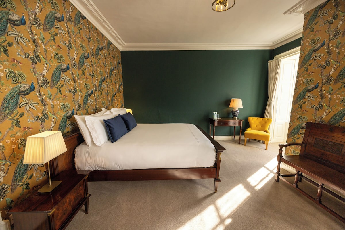 A bedroom with a bed, a nightstand, a lamp, a chair, and a dresser.