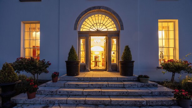 A grand entrance with a large arched doorway, flanked by two potted topiaries and a set of stone steps leading up to it. - Noan Country House B and B (Noan)