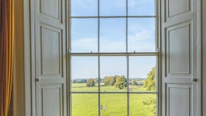 A room with a large window, a chair, and a plaid carpet. - Noan Country House B and B (Noan)