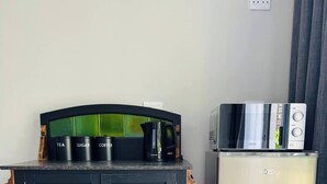 Eine Küchenzeile mit einem schwarzen Schrank, einer Kaffeemaschine und einem Minikühlschrank.