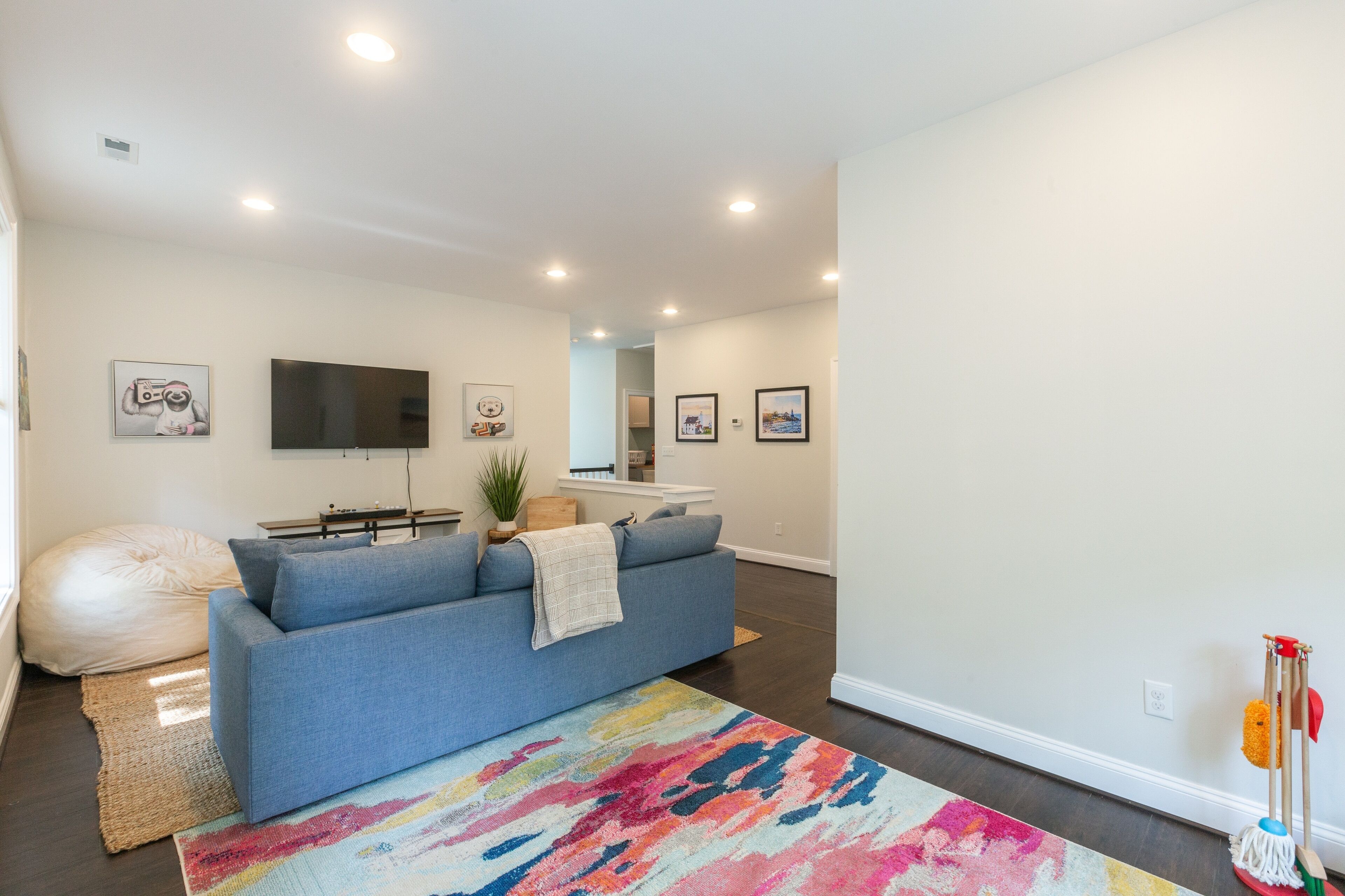 A modern living room with a blue sofa, colorful rug, and a flat-screen TV.