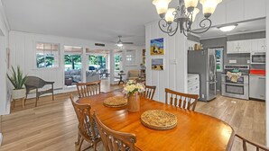 Un vaste espace dédié à la salle à manger, avec une table en bois, des chaises et un vase rempli de fleurs.