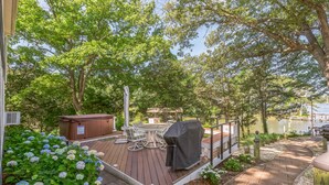 Une terrasse en bois avec des meubles d’extérieur, un barbecue et un jacuzzi.