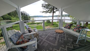 Relax in a serene lakeside setting with a view of lush greenery, surrounded by a patterned rug and comfortable seating.