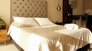 A neatly made bed with a tufted headboard, a bedside table with a plant, and a mirror on the wall. - Loft Pool Loft in Chapultepec (Guadalajara)