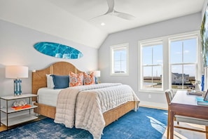 A bedroom with a bed, a ceiling fan, a large window, and a view of the outside. - Sweet Retreat 405 RET (Port Aransas)
