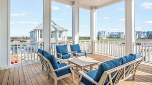 A covered outdoor area with wooden furniture and a view of the beach and buildings. - Sweet Retreat 405 RET (Port Aransas)