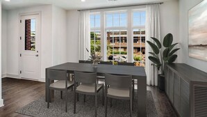 Ein moderner Essbereich mit einem dunklen Holztisch und Stühlen, großen Fenstern mit weißen Vorhängen und Blick auf ein Gebäude mit Balkonen.