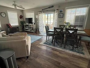 A living room with a sofa, a TV, a dining table with chairs, and a ceiling fan. - Spacious 5-bedroom house in beautiful Belmar w/ WiFi. 2 blocks from the beach! (Belmar)
