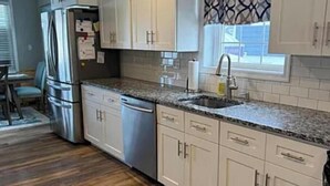 A kitchen with white cabinets, a stainless steel refrigerator, a dishwasher, and a granite countertop. - Spacious 5-bedroom house in beautiful Belmar w/ WiFi.  2 blocks from the beach! (Belmar)