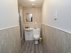 A compact bathroom with a sink, toilet, and mirror. - The Newborough Apartment 1 (Scarborough)