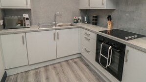 A modern kitchen with a microwave, sink, stove, oven, and cabinets. - The Newborough Apartment 1 (Scarborough)