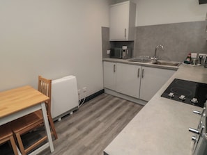 A compact kitchen with a wooden table, a built-in microwave, a sink, and a stove. - The Newborough Apartment 1 (Scarborough)