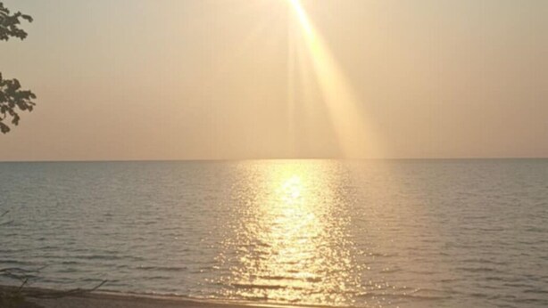 Een strandscène met zonlicht dat op het water weerkaatst.