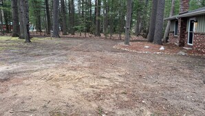 Una propiedad residencial con un patio amplio rodeado de altos pinos.
