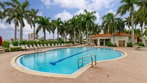 A swimming pool with lounge chairs and palm trees.