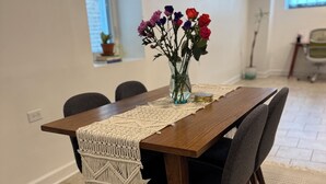 Une table à manger agrémentée d’un chemin de table en macramé, d’un vase de fleurs et d’un tapis à motifs.