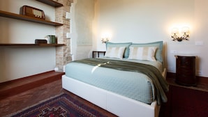 A bedroom with a bed, shelves, a rug, and a wall-mounted light fixture. - Central  Romantic nest San Gimignano (San Gimignano)